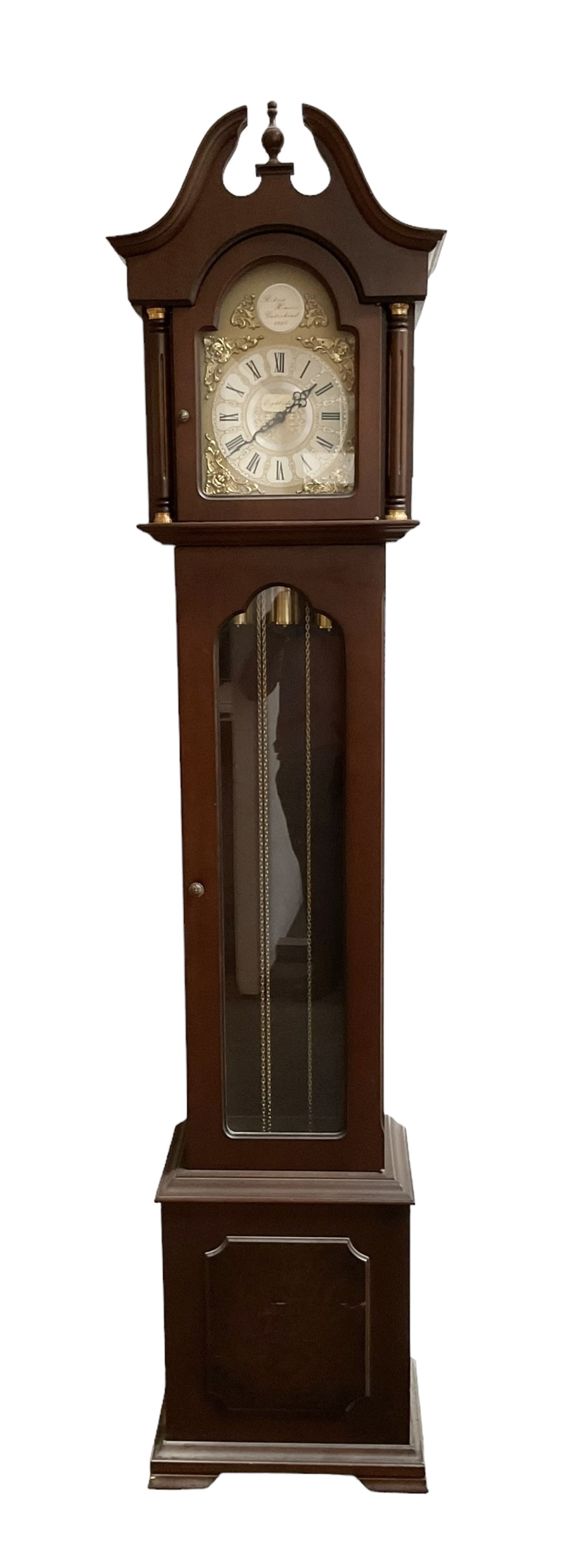 20th century - 8-day Mahogany longcase clock, with a swans necked pediment and break arch hood door beneath,  glazed door with visible brass cased weights and pendulum, on a rectangular plinth with a raised panel and bracket feet, brass dial with a silvered dial centre and chapter ring, chain driven three train movement chiming the quarters and hours on gong rods. With weights and pendulum.  