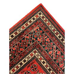 Persian design red ground rug, the field decorated with geometric motifs, repeating multiple band border 