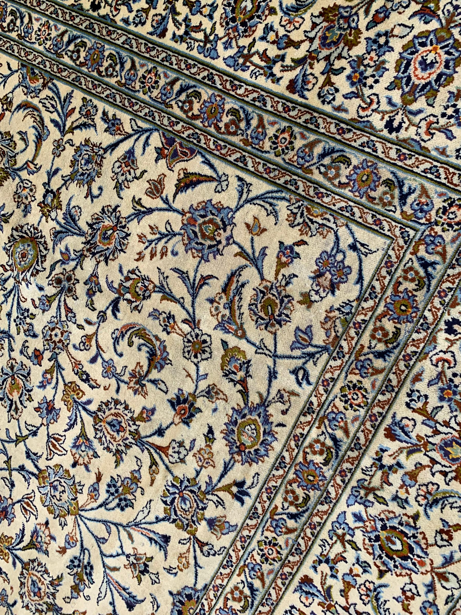 Persian Kashan ivory ground carpet, the field decorated with interlacing leafy branches and stylised plant motifs, repeating border with multiple guards