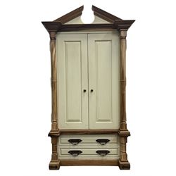 Hardwood and cream painted kitchen larder cupboard, sloped pediment over two panelled doors, the interior fitted with slides, drawers and storage shelves, two long drawers below, mounted by turned pilasters, on metal bound moulded plinth base