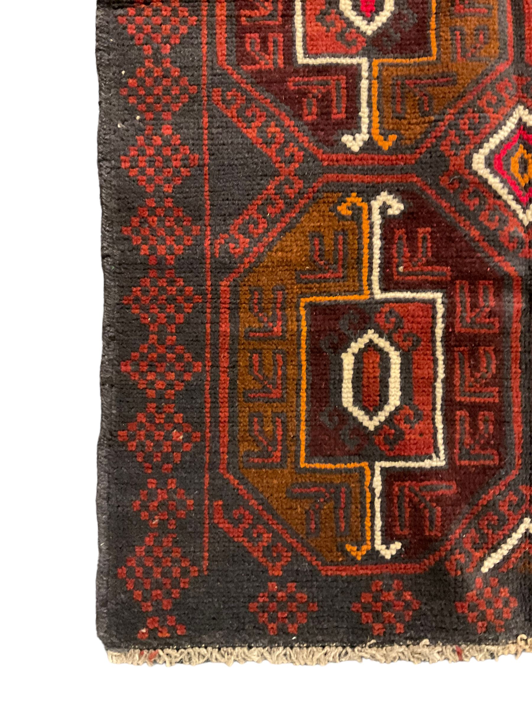 Baluchi red and blue ground rug, the field decorated with large six Gul motifs