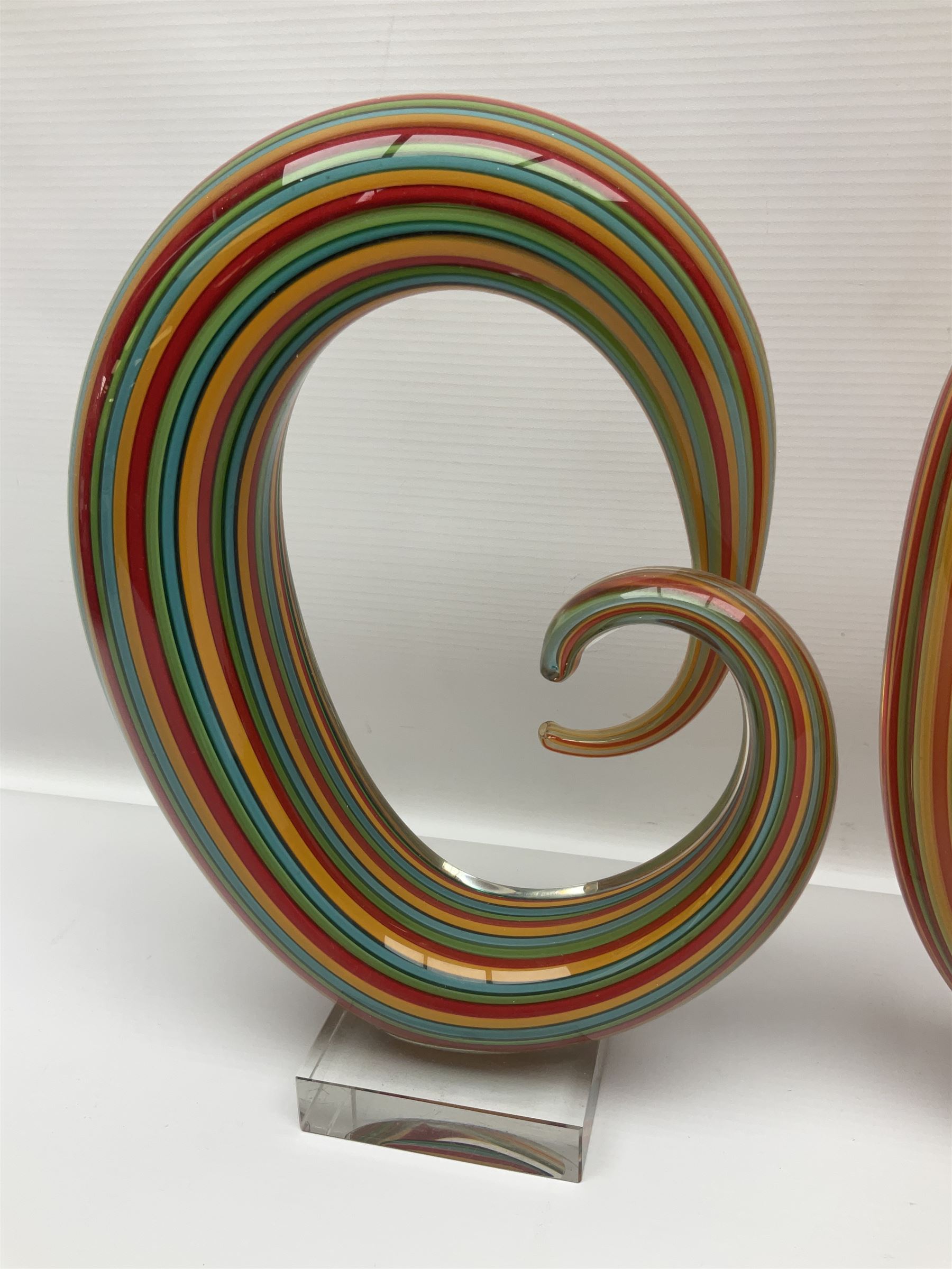 Three art glass sculpture, coiled form with multicolour stranded, upon clear glass plinth, unsigned, largest H27cm