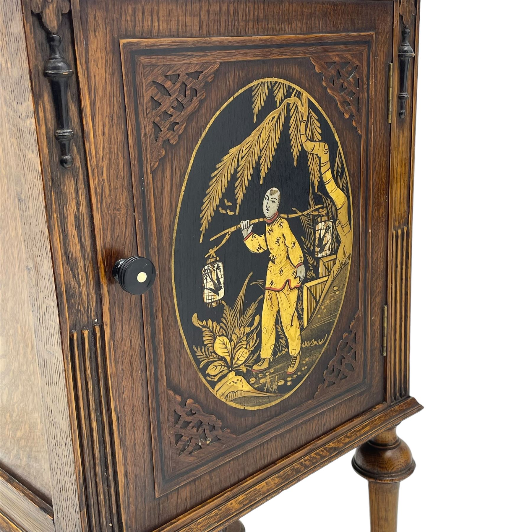 Early 20th century circa. 1920s oak bedside cupboard, raised back decorated with chinoiserie lacquer work depicting bird and flowers, moulded top over single door decorated with figure carrying bird cages, on turned supports united by shaped moulded stretchers, scroll carved feet