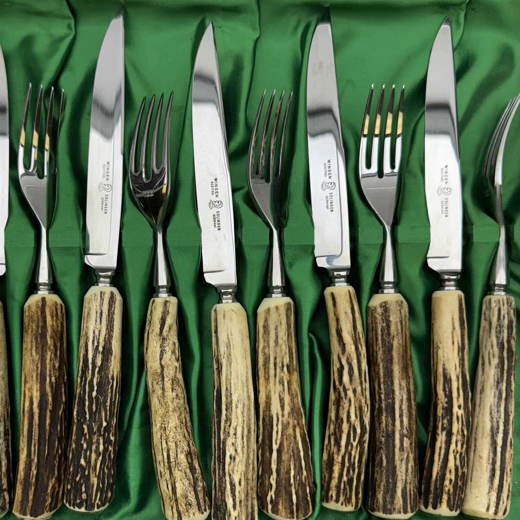 Set of six antler handled knives and forks by Wingen, together with a similar set by Hubertus, both in fitted trays 