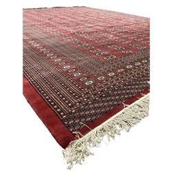 Large Persian Bokhara red ground carpet, the field decorated with eight rows of Gul motifs, wide multi-band borders decorated with repeating geometric motifs