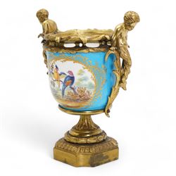 19th century French Sevres style porcelain and gilt brass urn, the body painted with panels of exotic birds and floral sprays within gilt borders on a bleu celeste ground, the handles formed as two cherubs seated upon grasses, upon a laurel leaf cast pedestal base, H20.5cm 