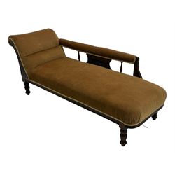 Late 19th century mahogany framed chaise longue, upholstered in tan fabric, featuring scrolled backrest with carved floral motifs, supported by turned legs