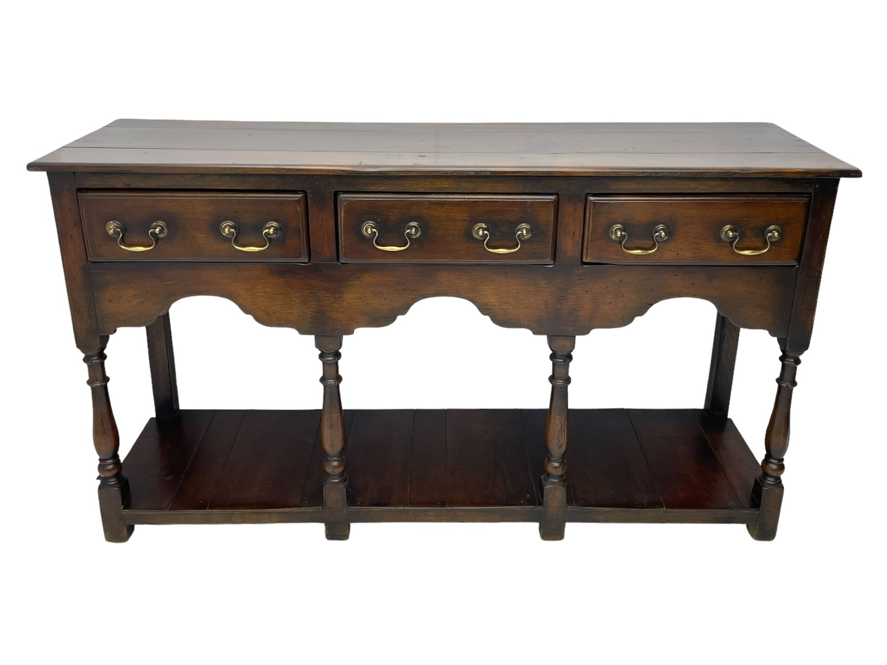 Georgian design oak dresser base, rectangular three plank top over three drawers and shaped apron, moulded drawer fronts with brass swan neck handles and circular plates, turned supports on panelled pot board base