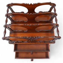 Victorian mahogany Canterbury, three divisions, carved with scrolls and curled leaf motifs, fitted with two drawers, on turned feet with brass cups and castors 