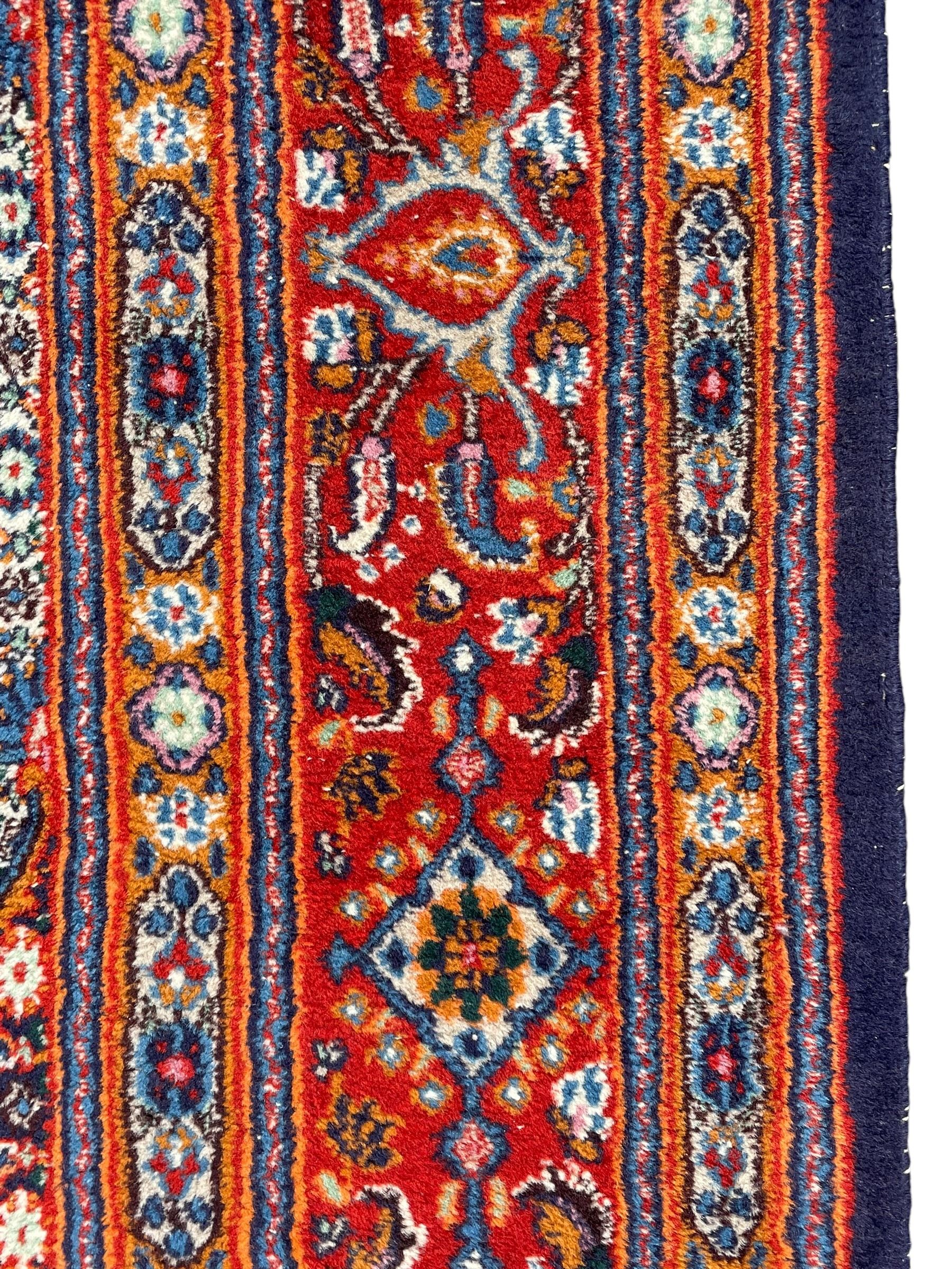 Persian Bidjar ivory and indigo ground rug, large central rosette medallion surrounded by floral herati motifs, crimson ground border decorated with repeating palmettes, within guard stripes decorated with small flower head motifs 