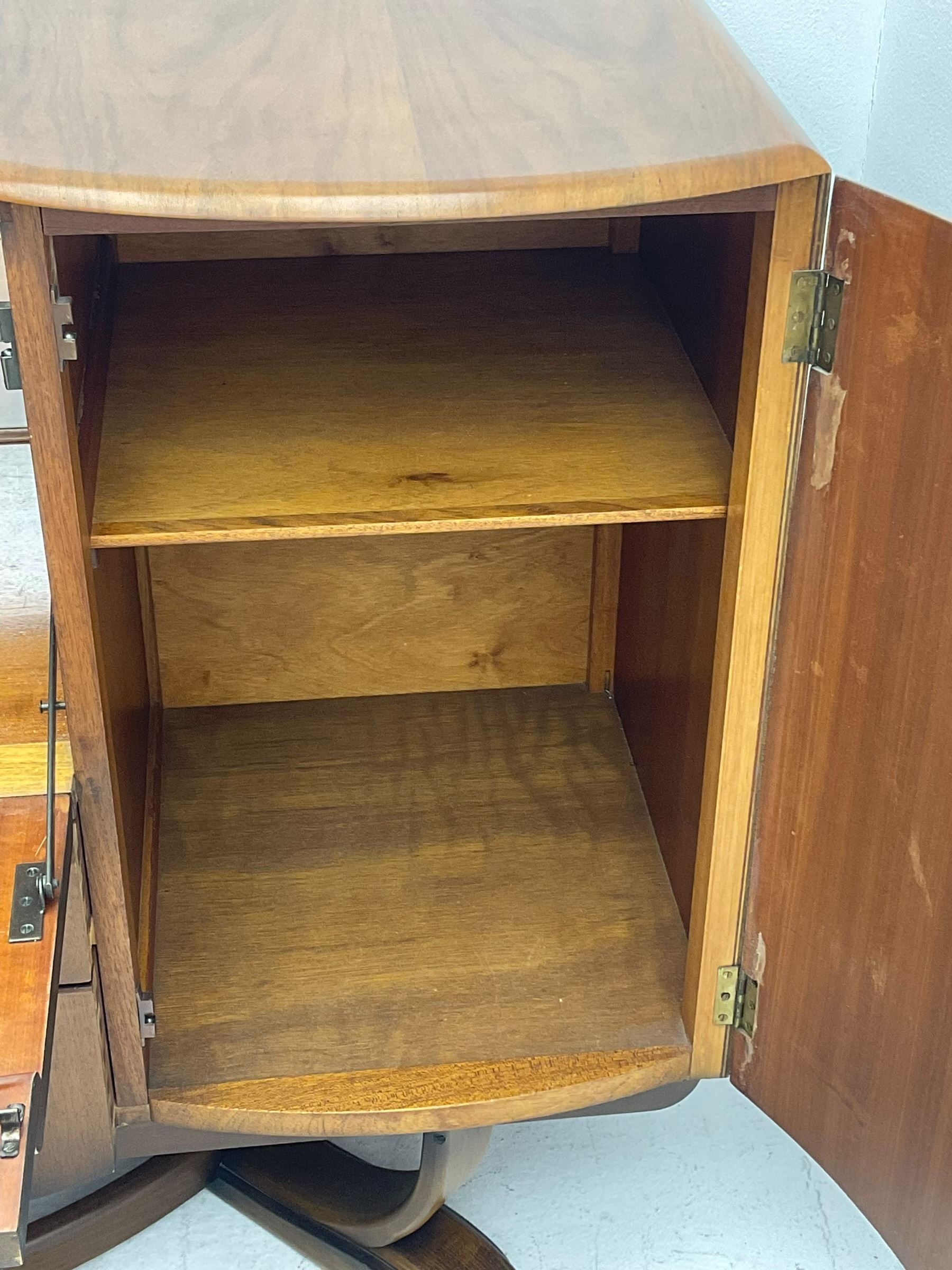 Beautility - mid-20th century walnut sideboard, fall-front with sliding top enclosing mirror interior, fitted with two drawers and flanking cupboards, on sledge feet with curved stretchers 