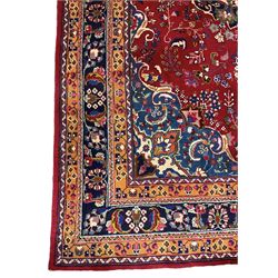 Persian Meshed red ground rug, central floral rosette medallion surrounded by trailing branch and stylised flower heads, repeating scrolling border