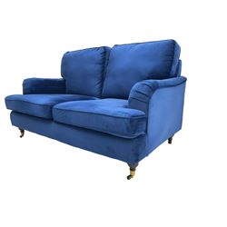 Howard design - two-seat sofa upholstered in blue fabric, traditional shape with rolled arms, on walnut finish turned feet with brushed metal cups and castors