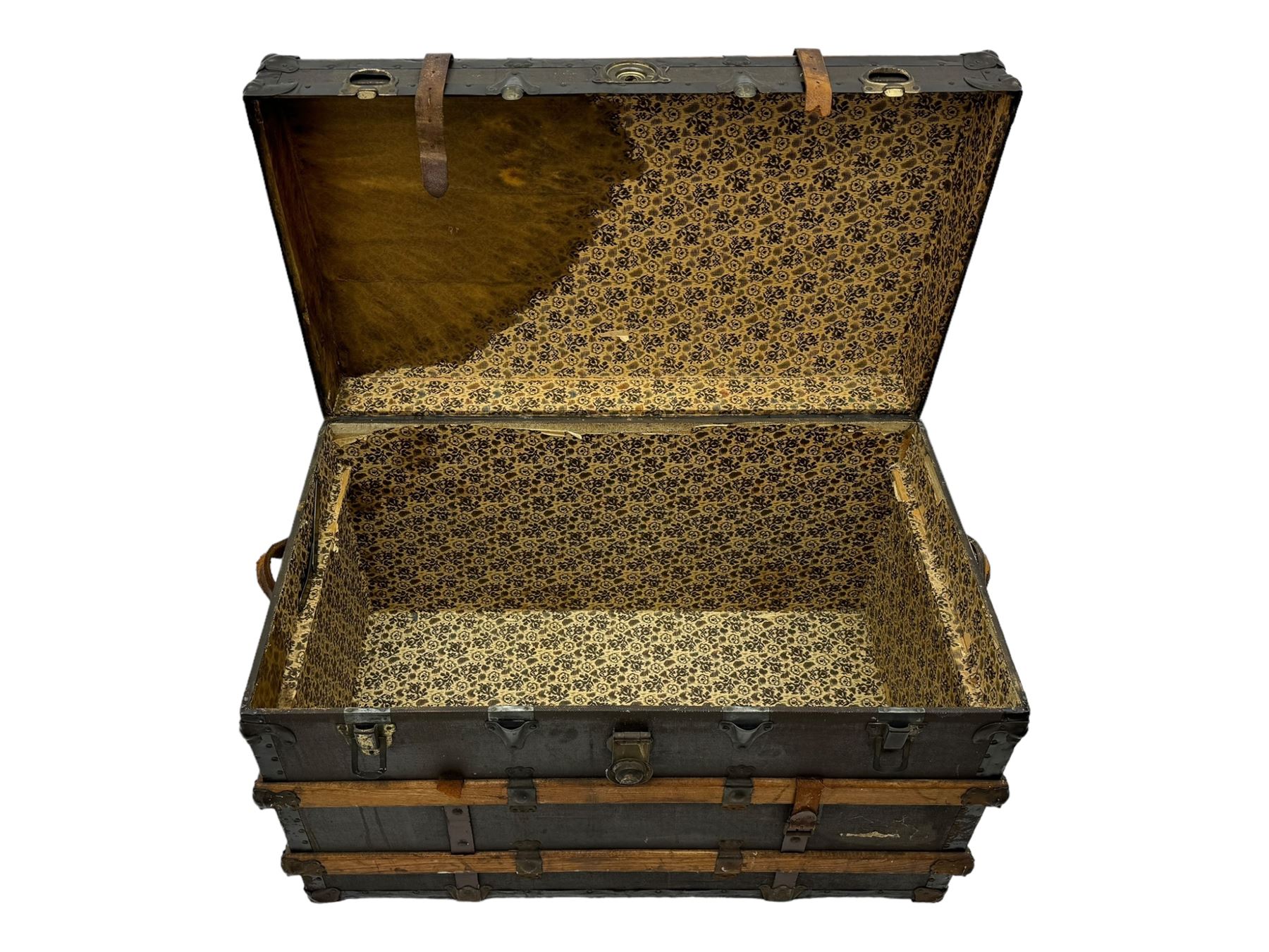 Early 20th century 'McBrine Baggage' steamer trunk, oak frame and black canvas covering, featuring metal hardware and leather straps, fitted with central lock, additional latches, and corner protectors, the interior is lined with floral-patterned paper and includes a removable top tray with makers label 