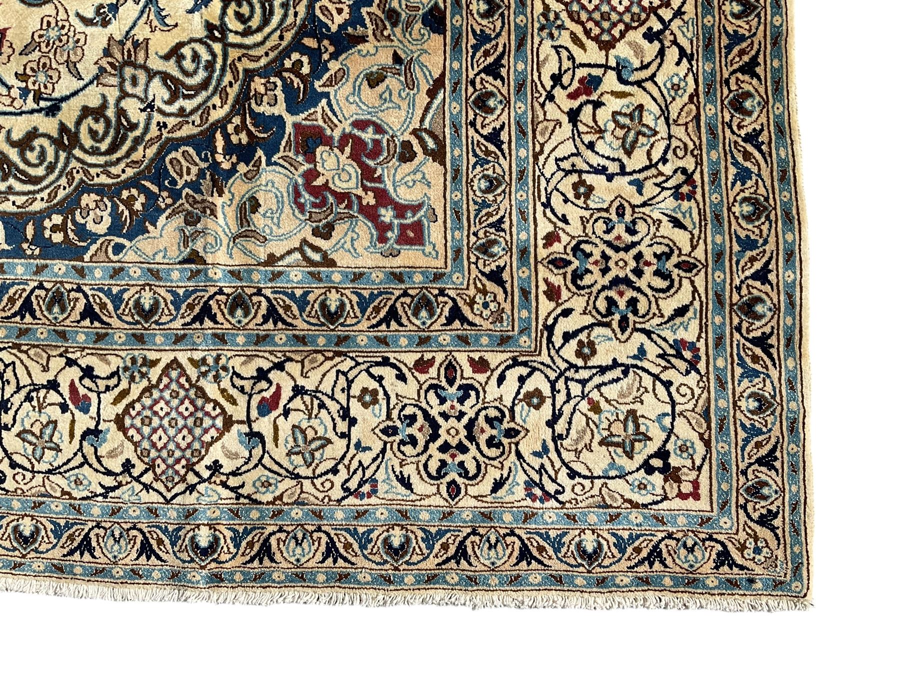 Persian Nain ivory ground carpet, central indigo medallion, the busy floral field decorated with scrolling vines and flower heads in shades of blue, beige, and red, wide guarded border with repeating palmettes and foliate motifs