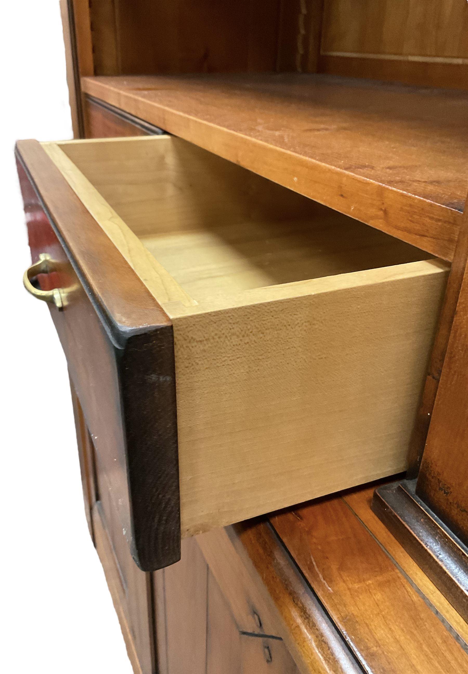 French cherry wood bookcase on cupboard, projecting moulded cornice over three shelves and two small drawers, the cupboard enclosed by two panelled doors flanked by fluted uprights