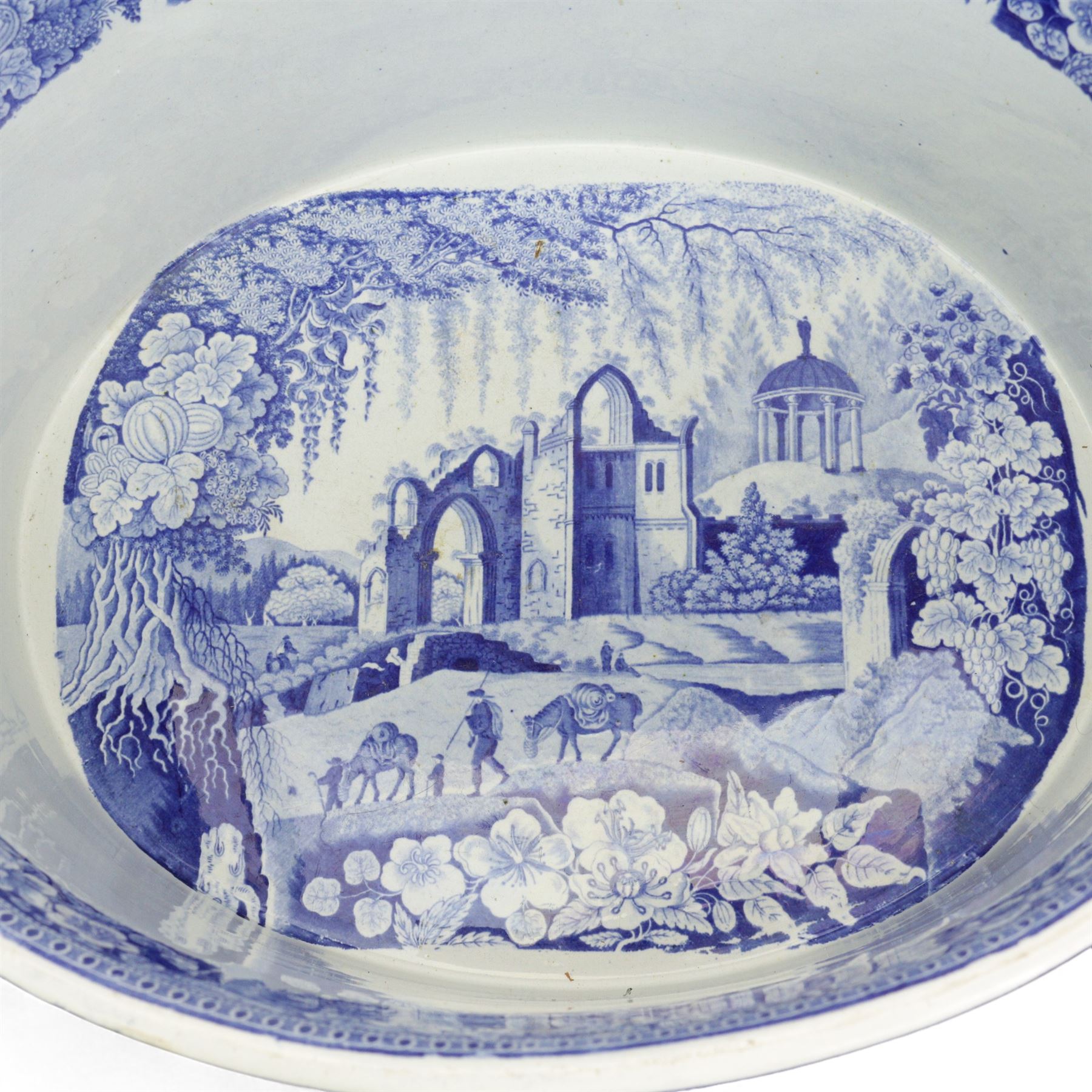 Early 19th century Staffordshire blue and white transfer printed footbath, of oval banded section, the exterior printed with a farmer herding cows down a country lane, the interior with figures and horses before a ruin, within floral borders, L52cm, H21cm, W36cm