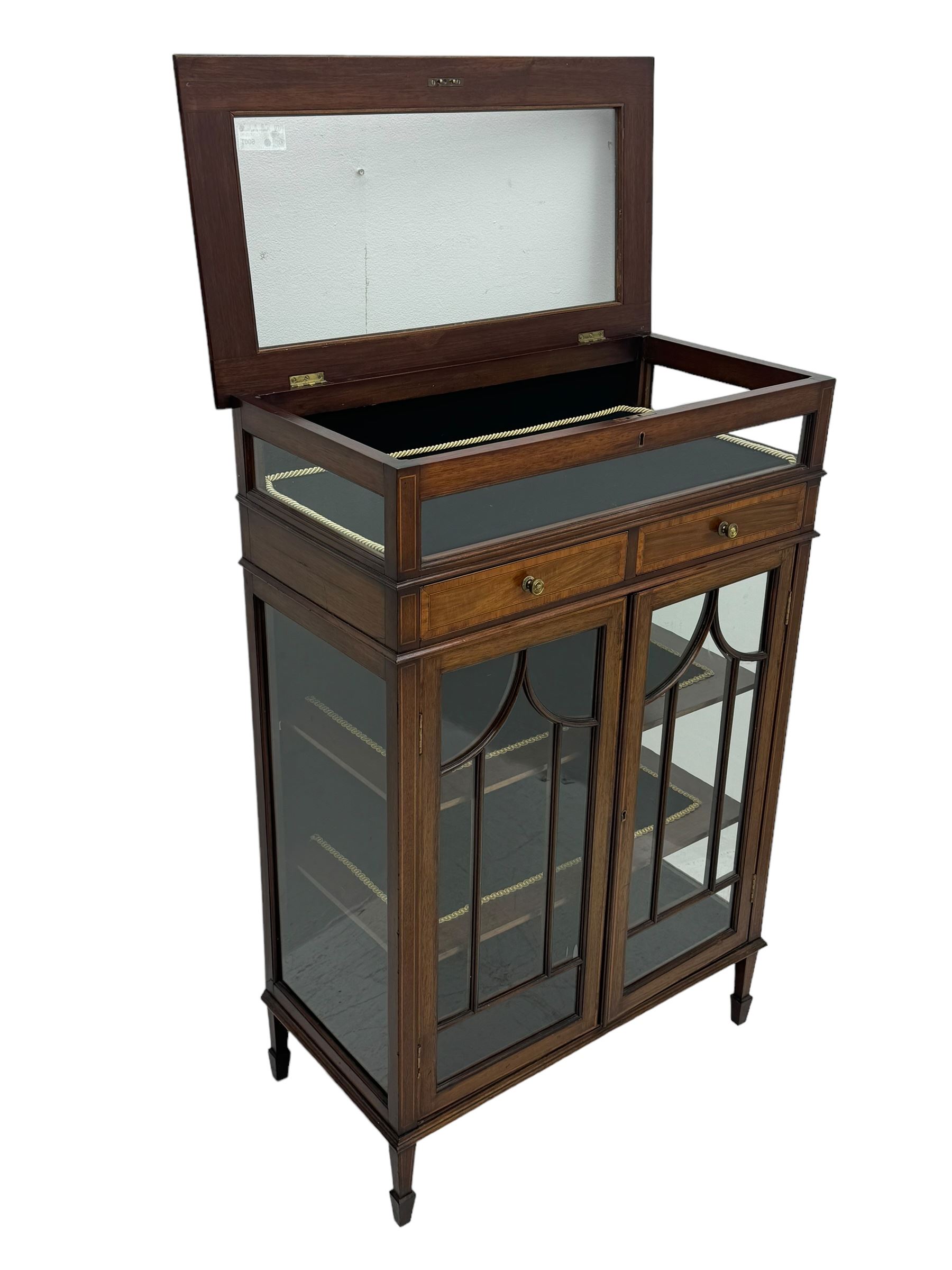 Edwardian mahogany bijouterie display cabinet, featuring satinwood inlay and crossbanding, hinged glazed top fitted with two banded drawers, over two astragal glazed doors enclosing black wool baize lined shelves with gold trim, supported by spade feet