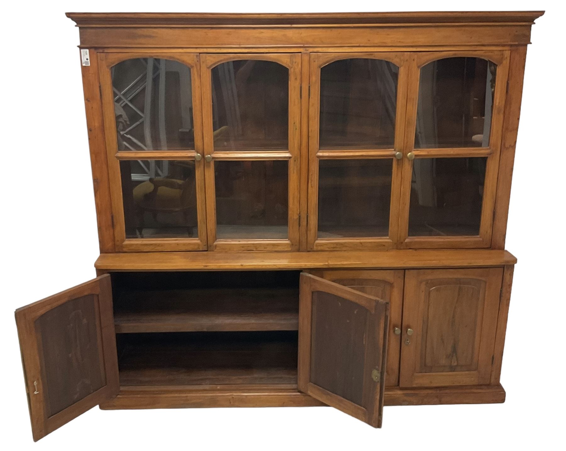 Mid-to-late 20th century Burmese teak wall cabinet, four glazed doors over four panelled doors, on moulded plinth base 