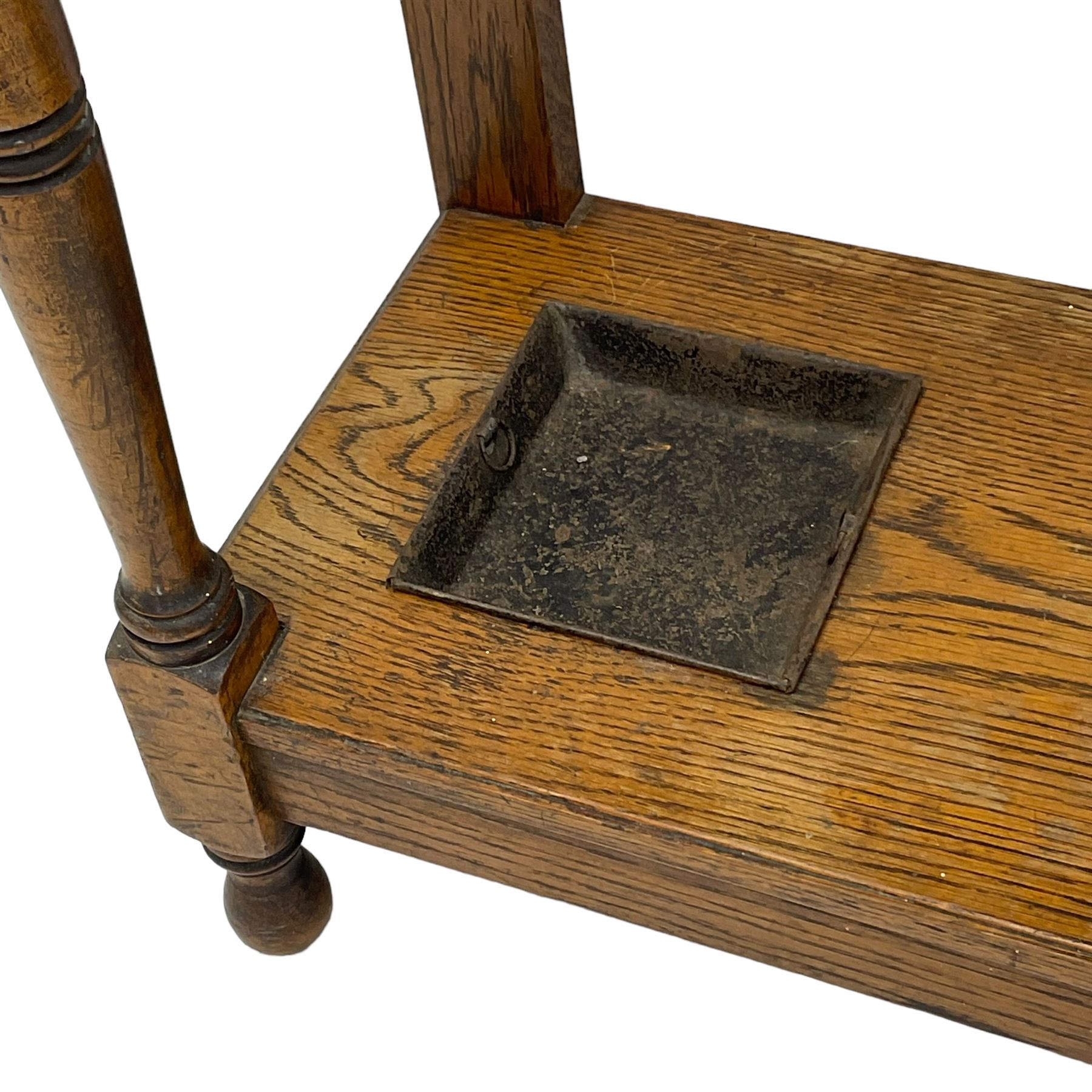 Early 20th century oak hall stand, bevelled mirror back over hinged compartment, on turned front supports 