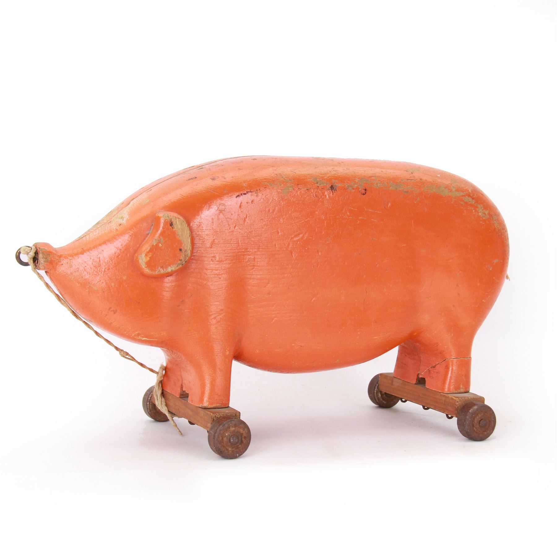 Mid 20th century scratch built pull along pig, the carved body painted orange, upon two wooden axels with metal wheels, H23cm