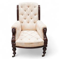 Victorian mahogany framed armchair, moulded and rolled uprights, upholstered in buttoned cream foliate pattern fabric, carved lion mask arm terminals, on turned and globular carved front feet, brass castors 