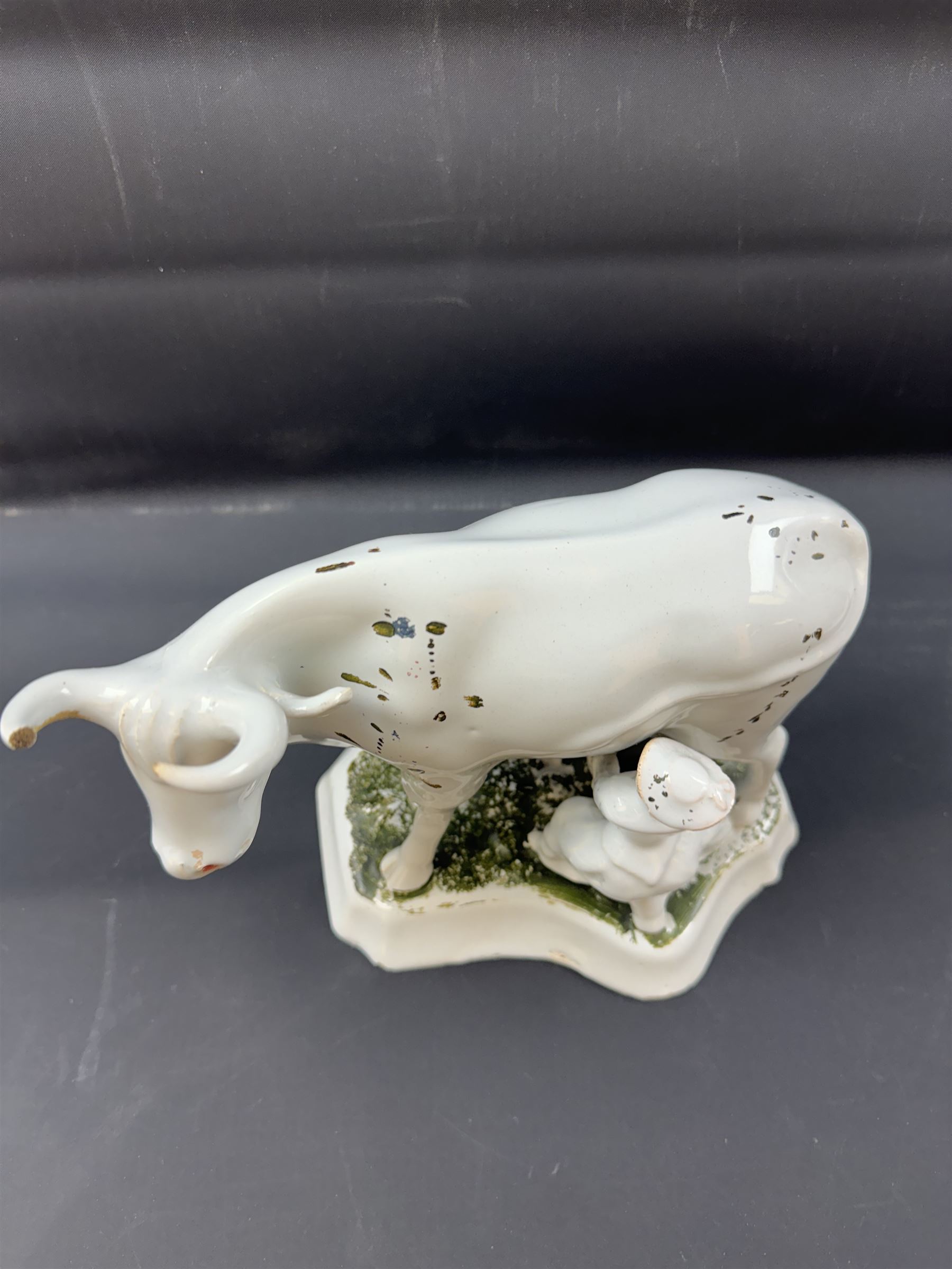 19th century Delft figure group depicting a milkmaid milking a cow, H17.7cm