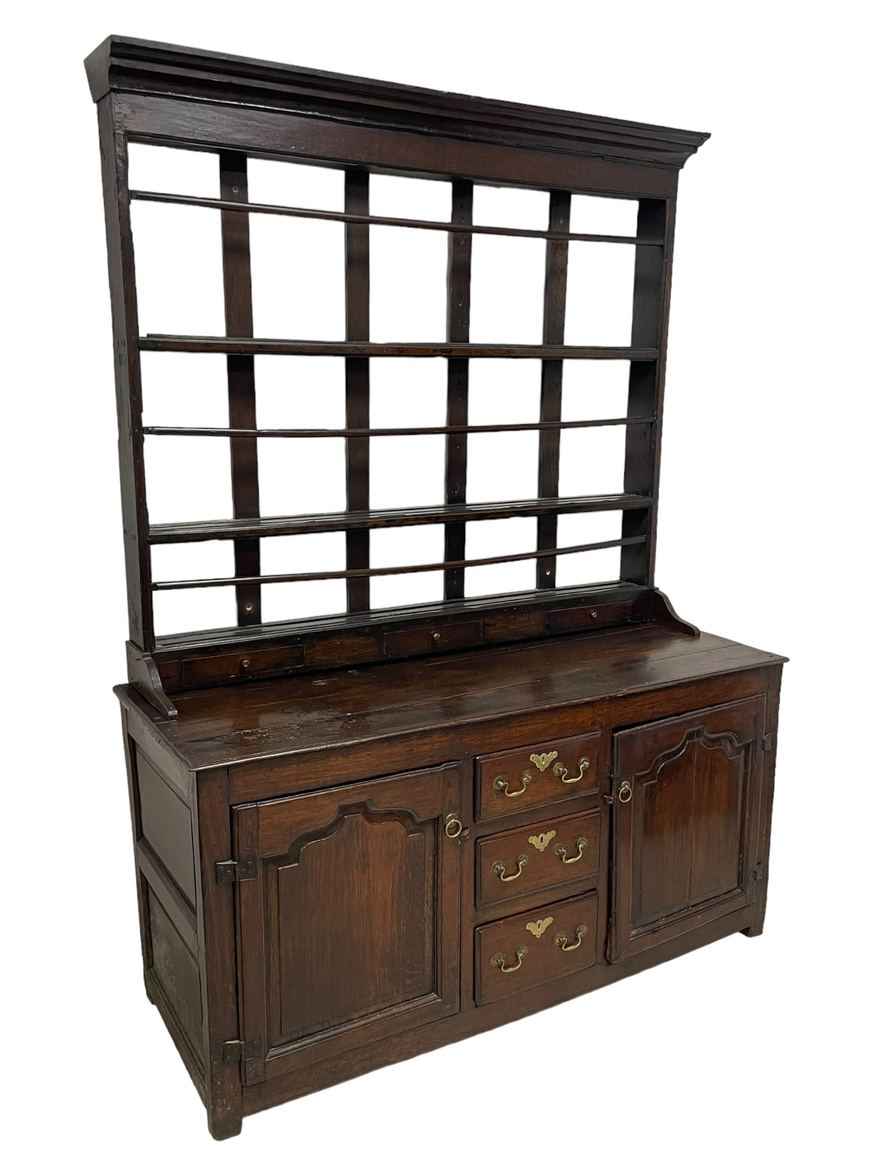 18th century oak dresser, projecting cornice over three heights plate rack with three small drawers, rectangular ovolo-moulded top over three central drawers and two flanking cupboards, enclosed by fielded panelled doors, on stile supports 