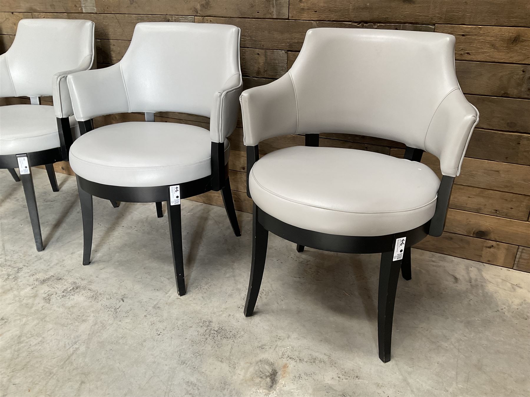 Four ebonised framed tub shaped armchairs, upholstered in grey fabric