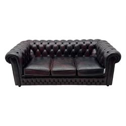 Chesterfield three-seat sofa, traditional shaped upholstered in deeply buttoned dark red leather; together with similar footstool 