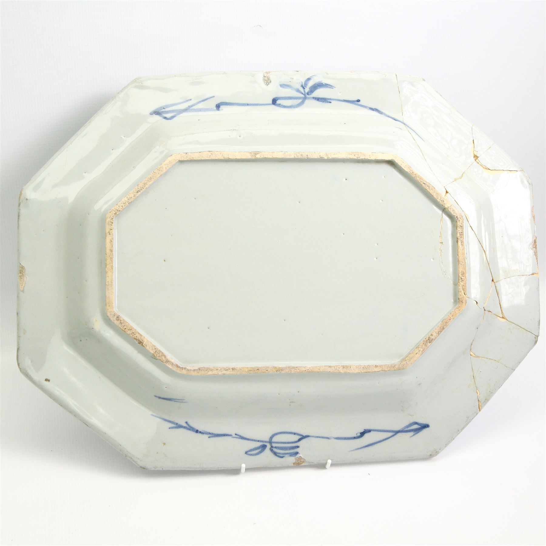 Two English Delft dishes, of canted rectangular form, painted with a fence, flowering plants and bamboo, within a scroll border, one marked F beneath, 49.5cm x 37.5cm max (2)