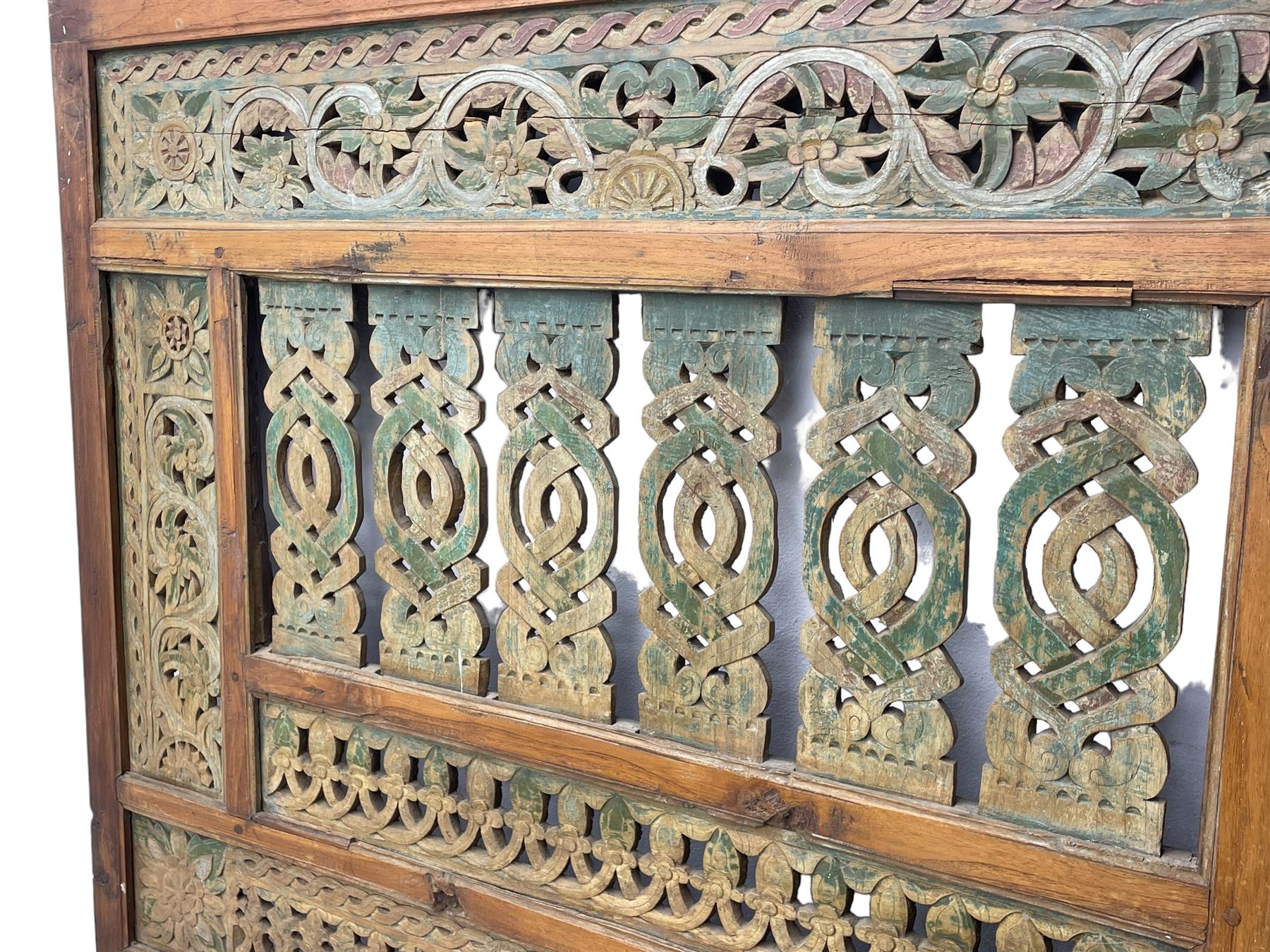 Early 20th century Javanese teak and hardwood door panel or room divider, rectangular panelled form with moulded frame and pegged construction, carved and pierced with scrolling decoration and flower head motifs, shaped and pierced splats with interlocking pattern