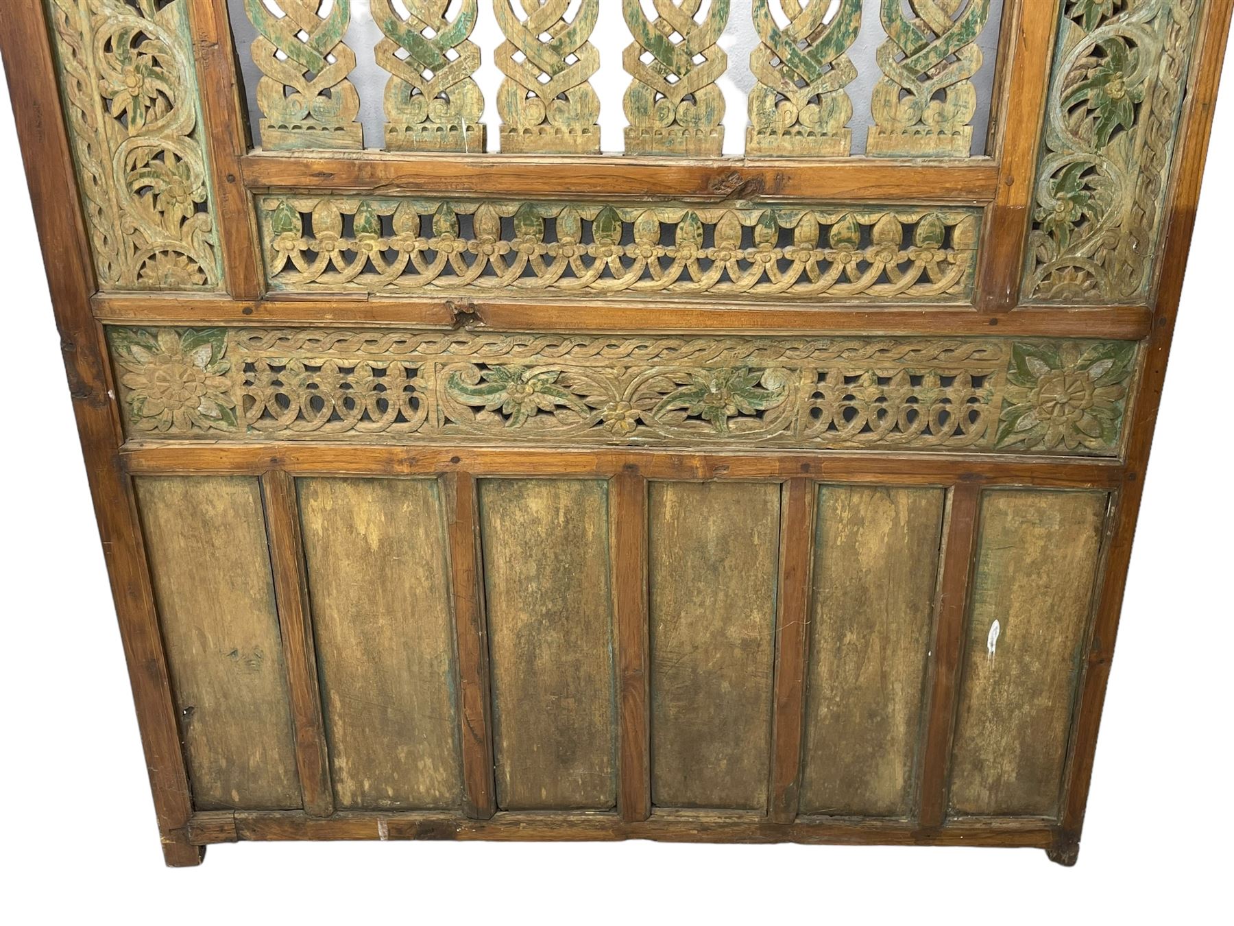 Early 20th century Javanese teak and hardwood door panel or room divider, rectangular panelled form with moulded frame and pegged construction, carved and pierced with scrolling decoration and flower head motifs, shaped and pierced splats with interlocking pattern