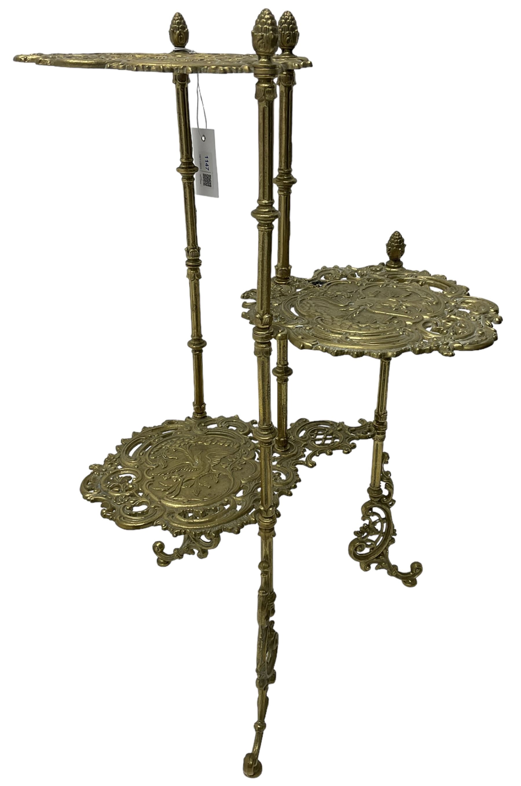 Cast gilt metal three-tier cake stand, each tier decorated with cast foliage scrolls and flower heads with a central bird motif, on turned and fluted supports with splayed C-scroll feet