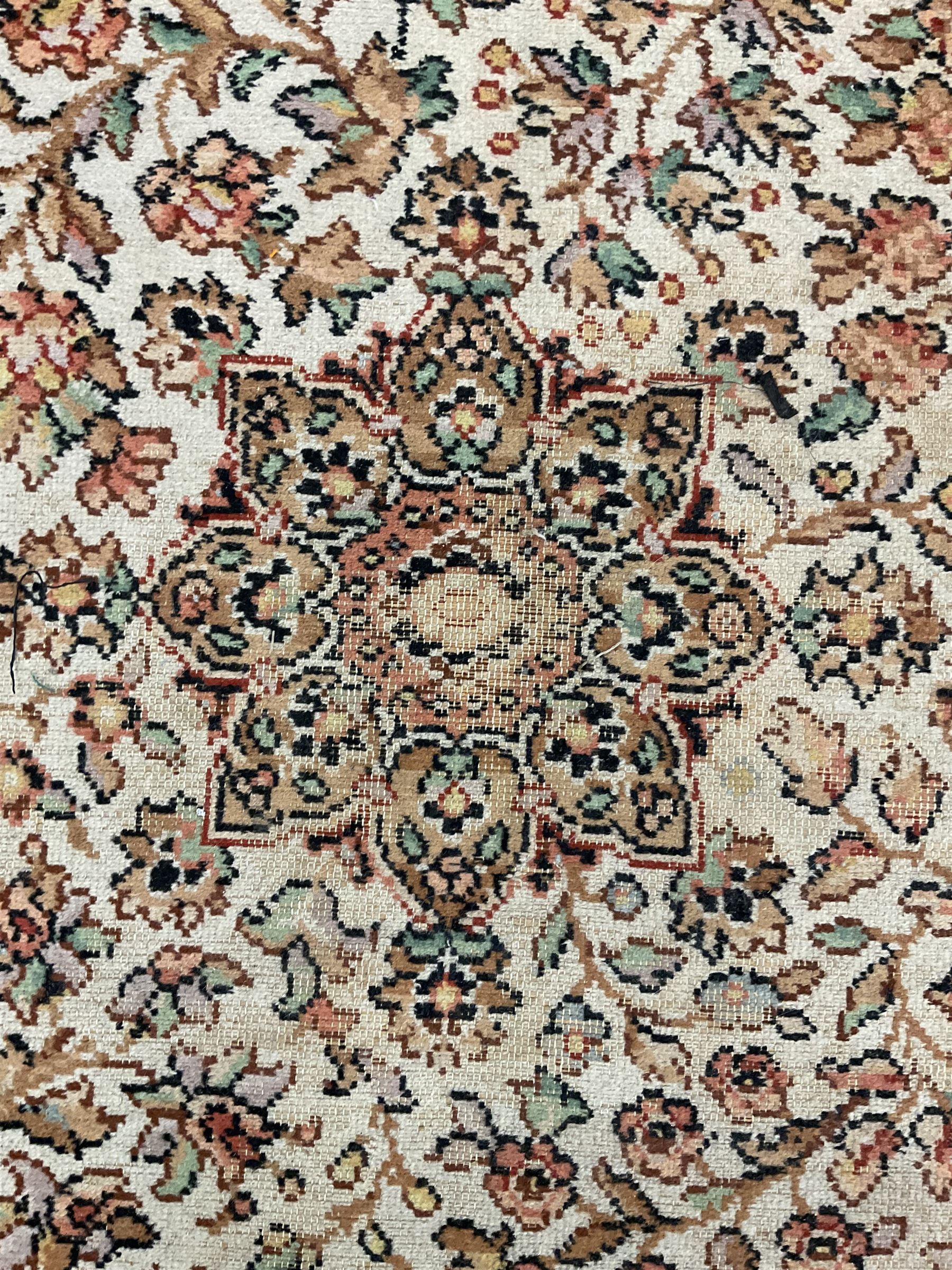 Large Persian design carpet, overall floral design, the field decorated with large rosette motifs surrounded by trailing foliate motifs, the border decorated with trailing branch and stylised plant motifs