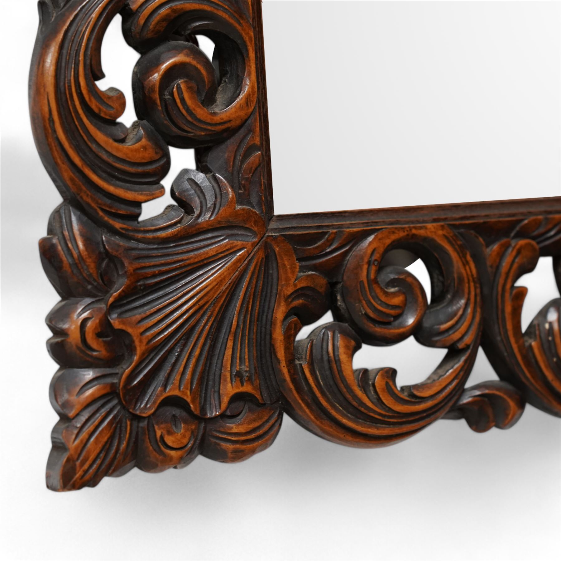 Early 20th century walnut framed wall mirror, bevelled mirror plate enclosed by carved frame, decorated with curling foliage 