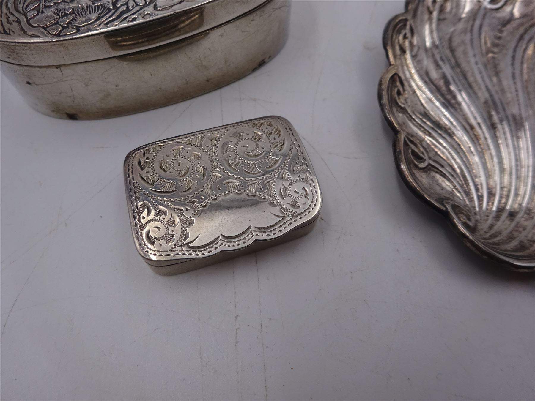 Modern silver oval box, decorated to the removable cover with an owl on a branch, hallmarked London 1984, makers mark KB, together with a modern silver pin tray of scrolling lobed form, hallmarked 1992, makers mark EM, and an early 20th century silver pill box, hallmarked Adie & Lovekin Ltd, Birmingham 1910, oval box H2.2cm, W6.5cm