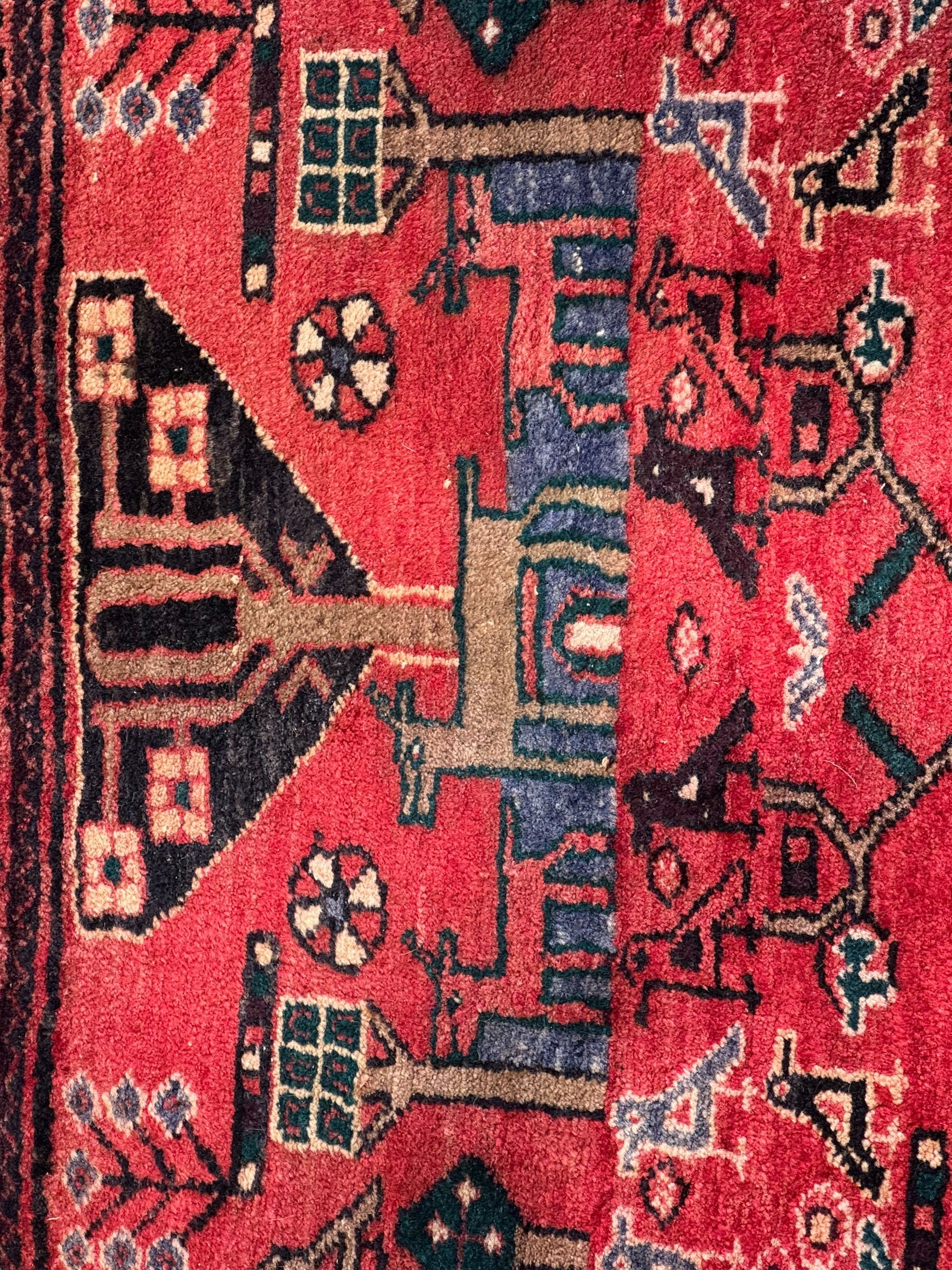 Persian crimson ground runner, the field decorated with stylised tree and animal motifs, indigo ground border decorated with alternating stylised flowerhead and bird motifs 