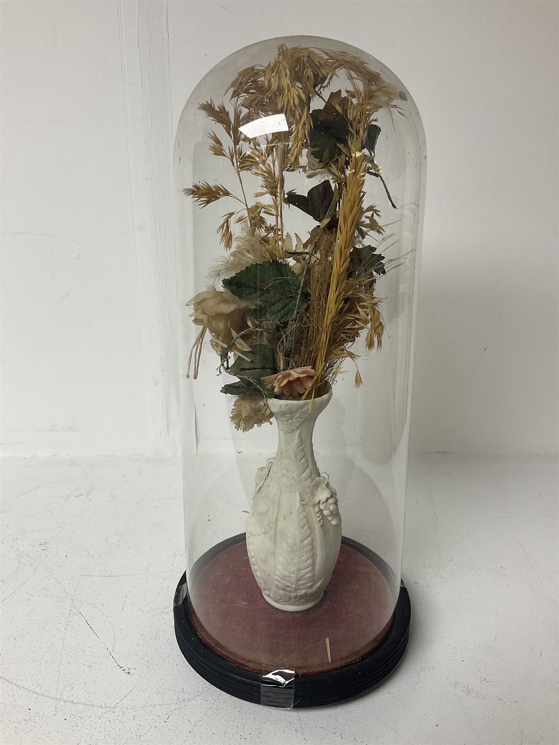 Victorian dome on ebonised wooden base, containing parian vase of silk and dried flowers, H47cm