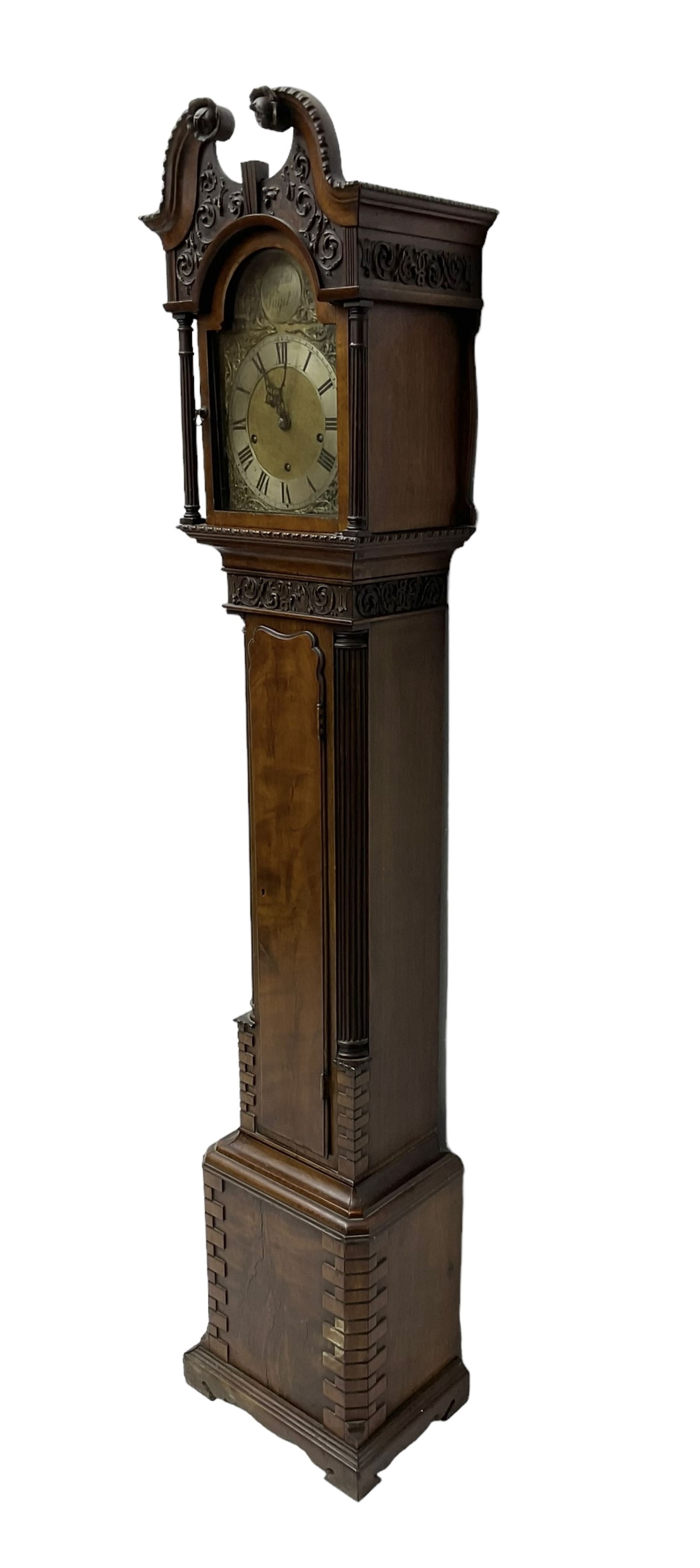 20th century - Chippendale design mahogany 8-day Grandmother clock with a profusely carved and decorated swan's' neck pediment, break arch hood door flanked by reeded pilasters with wooden capitals, trunk with a carved frieze, canted corners, three quarter reeded pilasters and a long trunk door with a wavy top, plinth with carved brickwork to the corners and raised on a shaped base, brass dial with a plain centre, cast spandrels and a silvered 