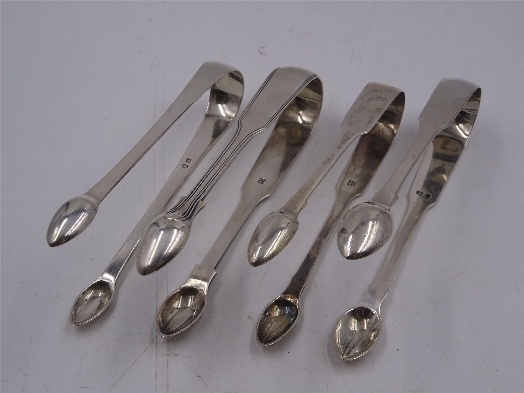 Four pairs of George III and later York silver sugar tongs, to include Fiddle pattern pair with reed borders and a plain pair, both hallmarked James Barber, George Cattle II & William North, and two plain Fiddle pattern pairs, one hallmarked James Barber & William Whitwell, the other hallmarked James Barber & William North, all engraved with initials 