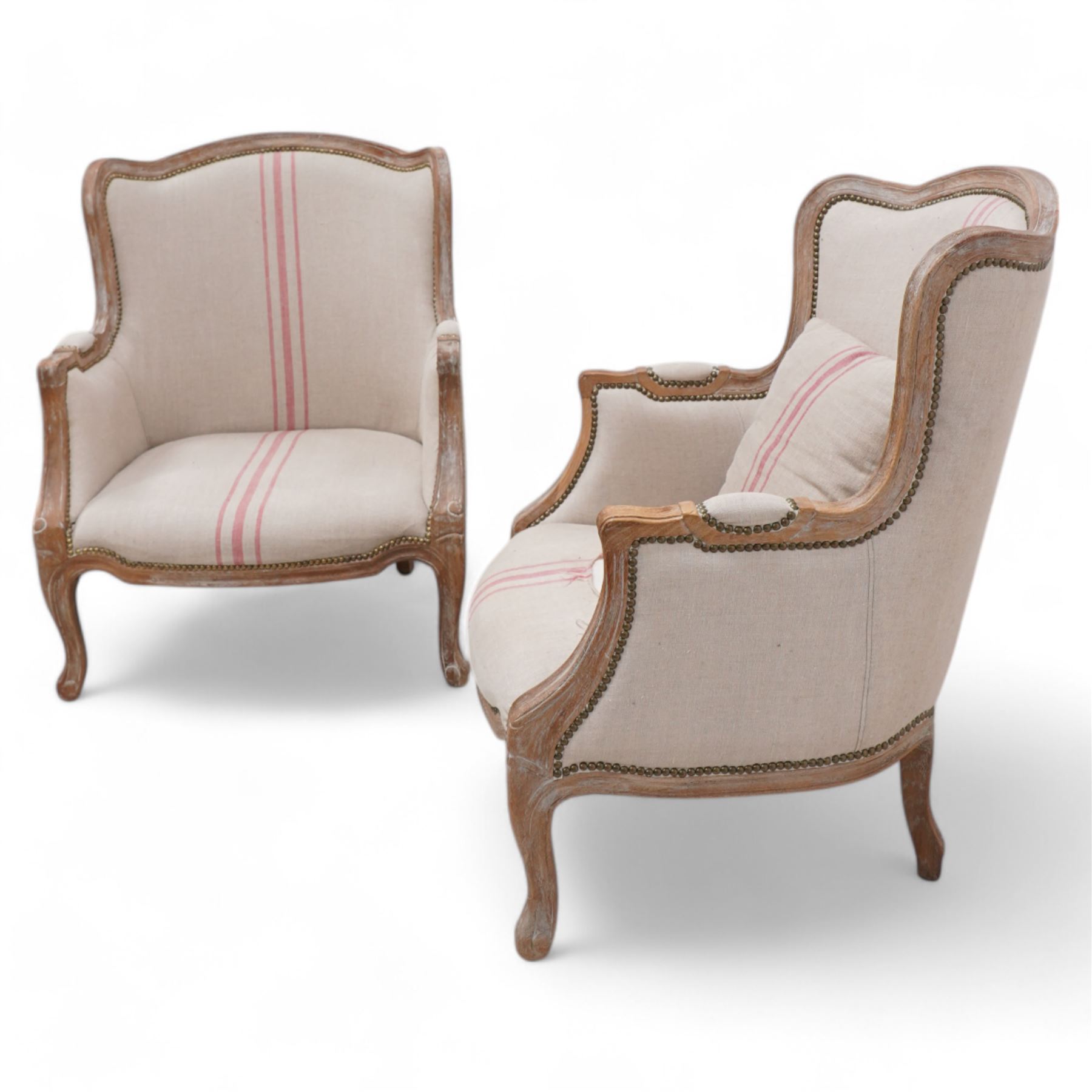 Pair of large hardwood-framed French design armchairs, moulded and shaped frames terminating to cabriole feet, upholstered in pale fabric with pink stripes 