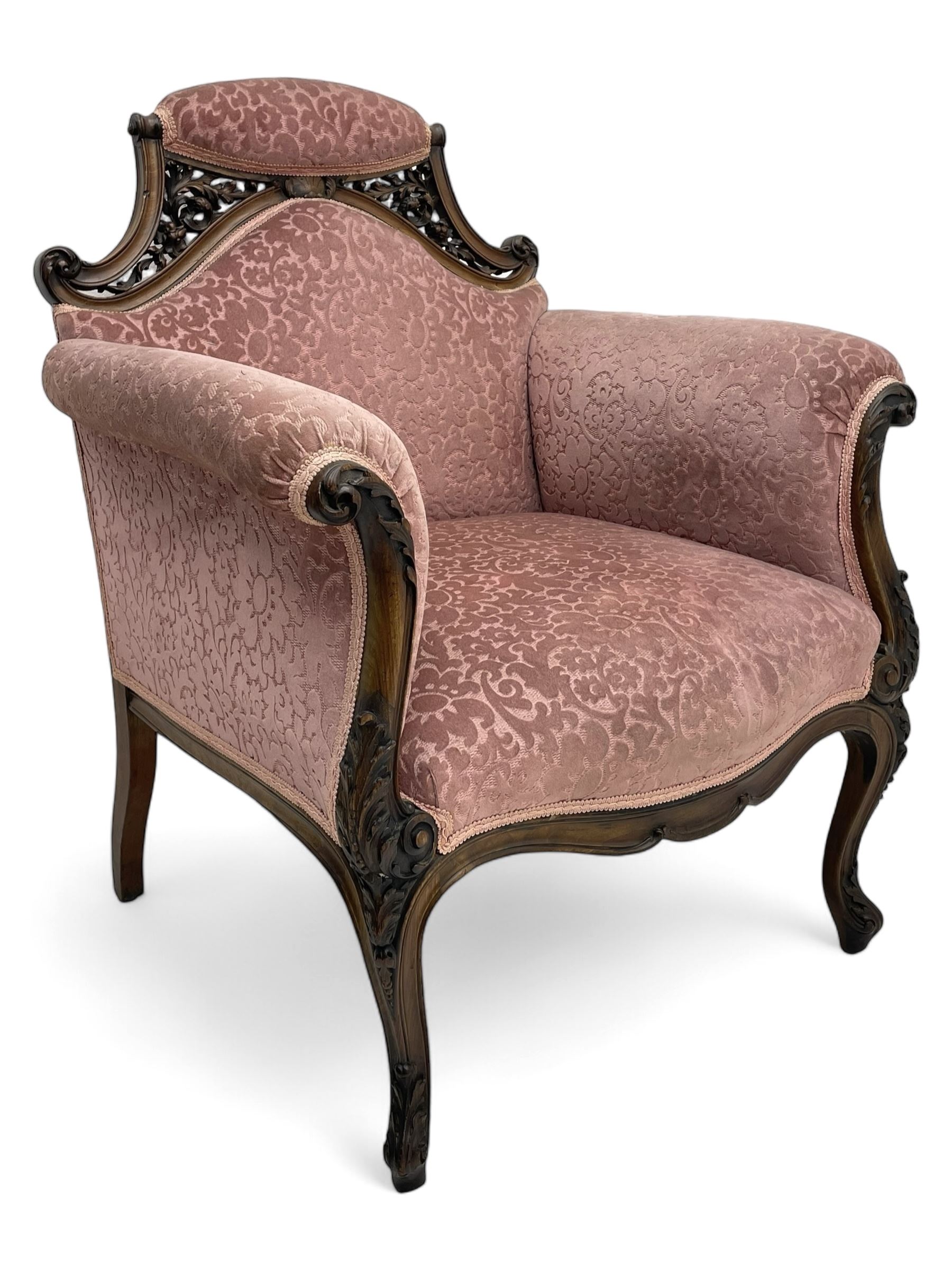 Late 19th century carved walnut framed armchair, the upper spandrels pierced and carved with curled acanthus leaves, upholstered in pink foliate pattern fabric, acanthus leaf carved and scrolled arm facias terminating to cabriole supports, leaf carved terminals 