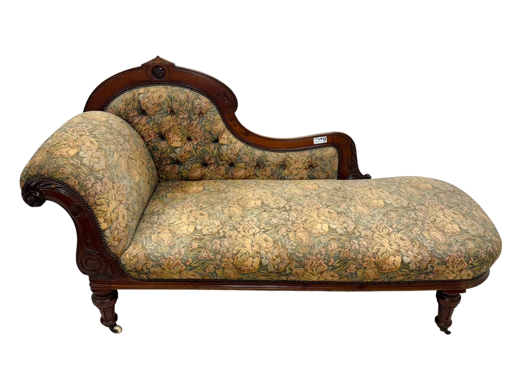 Victorian Aesthetic Movement mahogany framed chaise longue, shaped carved back over acanthus scrolled arm terminal, upholstered in floral patterned tapestry fabric with sprung seat, on turned and fluted supports with castors