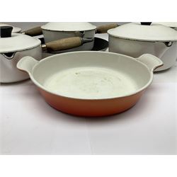Set of five white Le Creuset pans of graduating size together with matching frying pan and orange twin handled dish