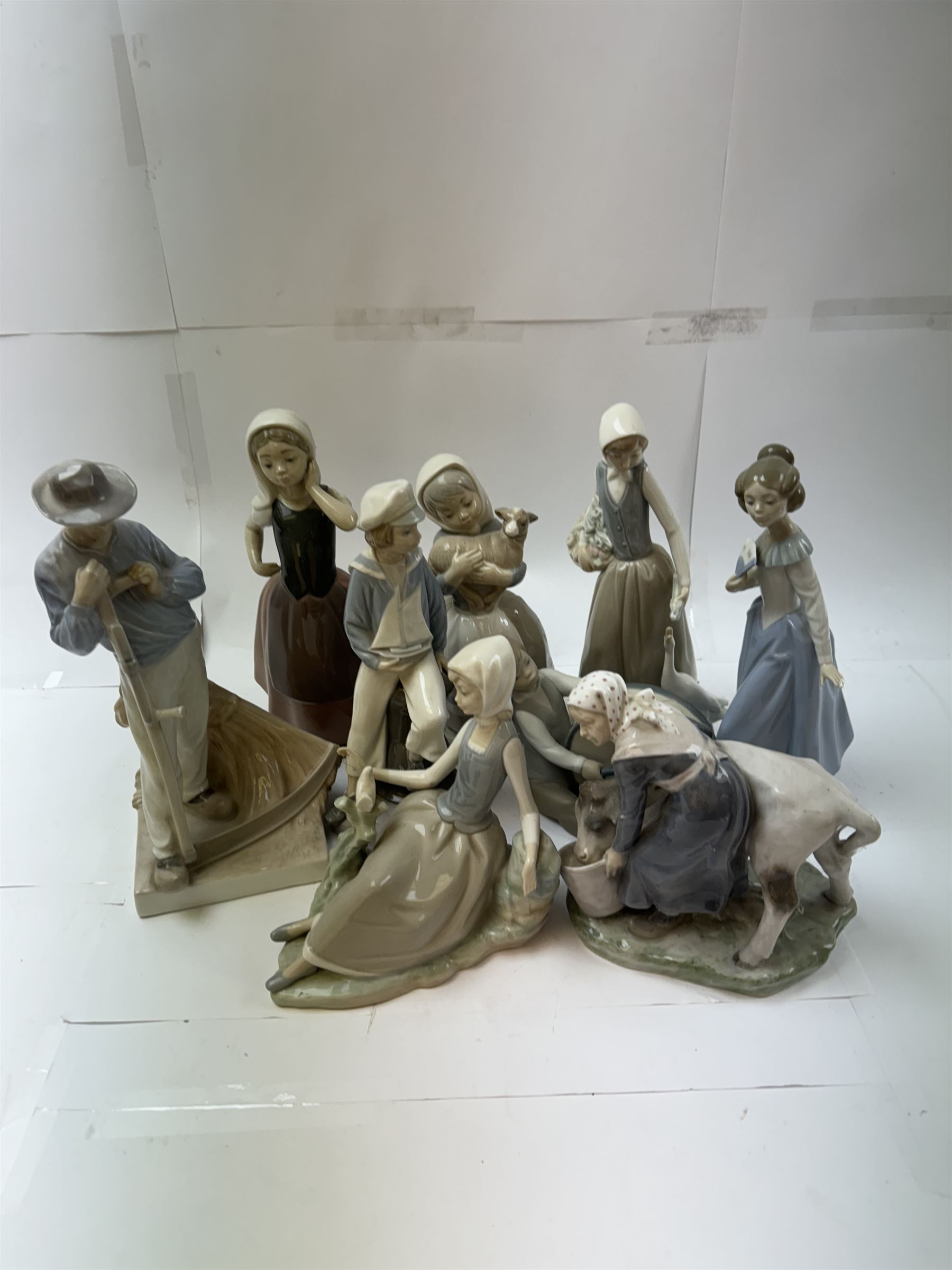 Two Royal Copenhagen figures, comprising girl with cow, 779 and Farmer with scythe, no 685 , together with two Lladro figures, and similar 