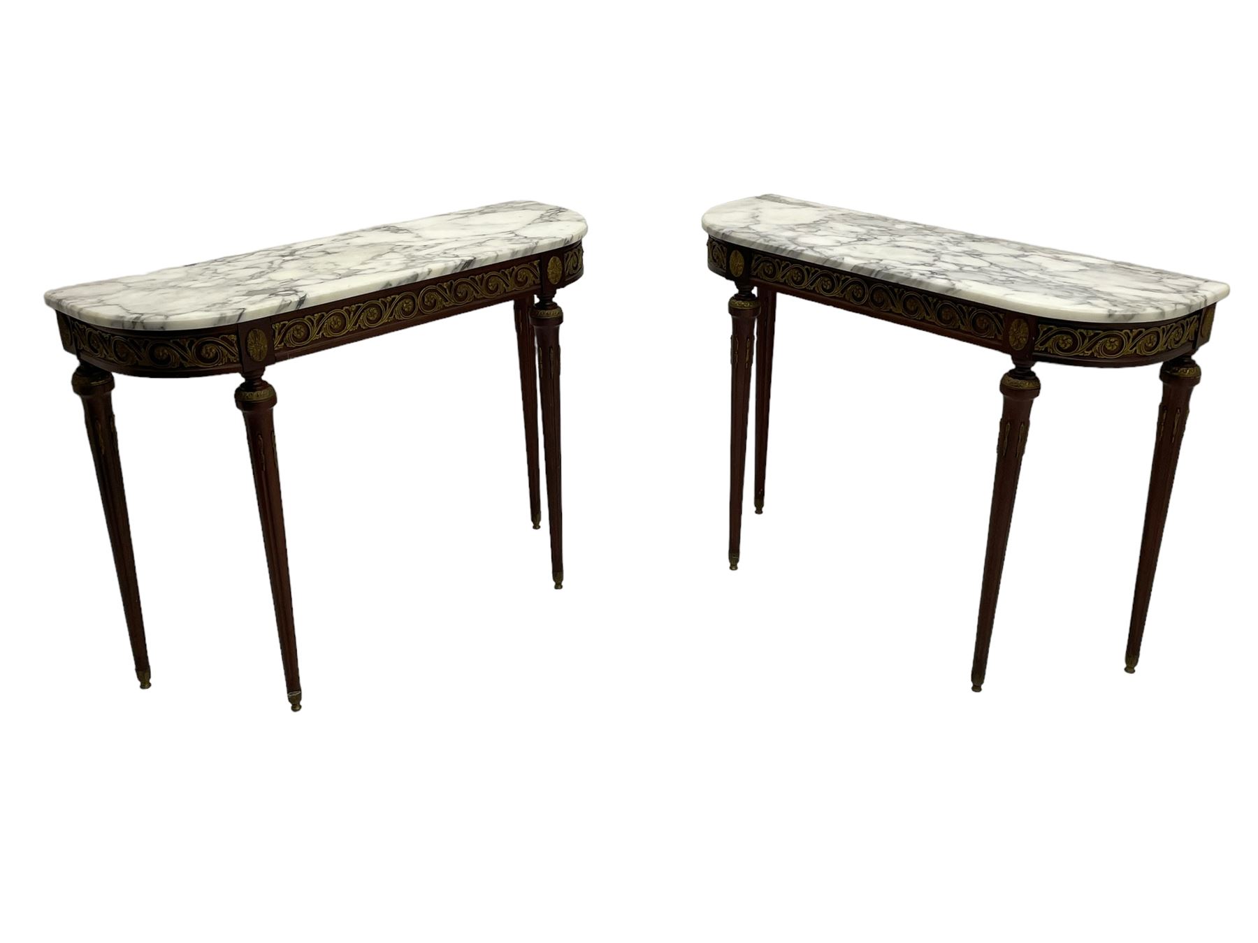 Pair of late 20th century French design mahogany console tables, D-end form with white and grey veined marble tops, the frieze rails decorated with scrolled leaf and flower head cast brass mounts, on turned and fluted supports with cast brass mounts and feet 