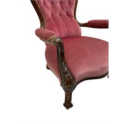 Victorian carved walnut open armchair, foliate carved cresting rail over butted back and sprung seat, upholstered in pink velvet scrolled arm terminals with moulded scrolling vines terminating to cabriole supports and ceramic castors