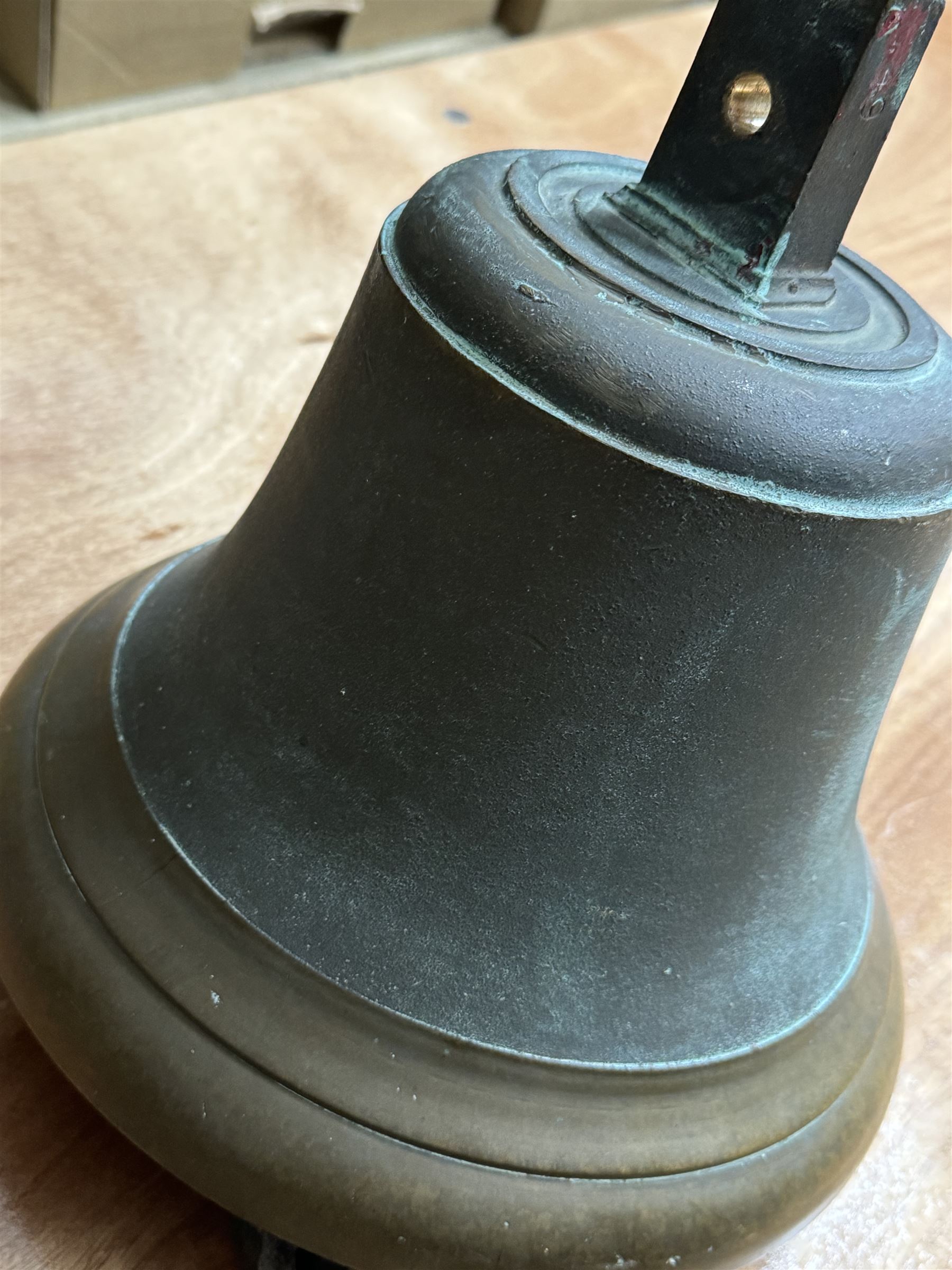 Late 19th century/early 20th century bell with rope pull, probably a fire bell, marked LCC G49 to canon, upon a black painted wrought iron wall mount, bell H29cm, mount H64cm