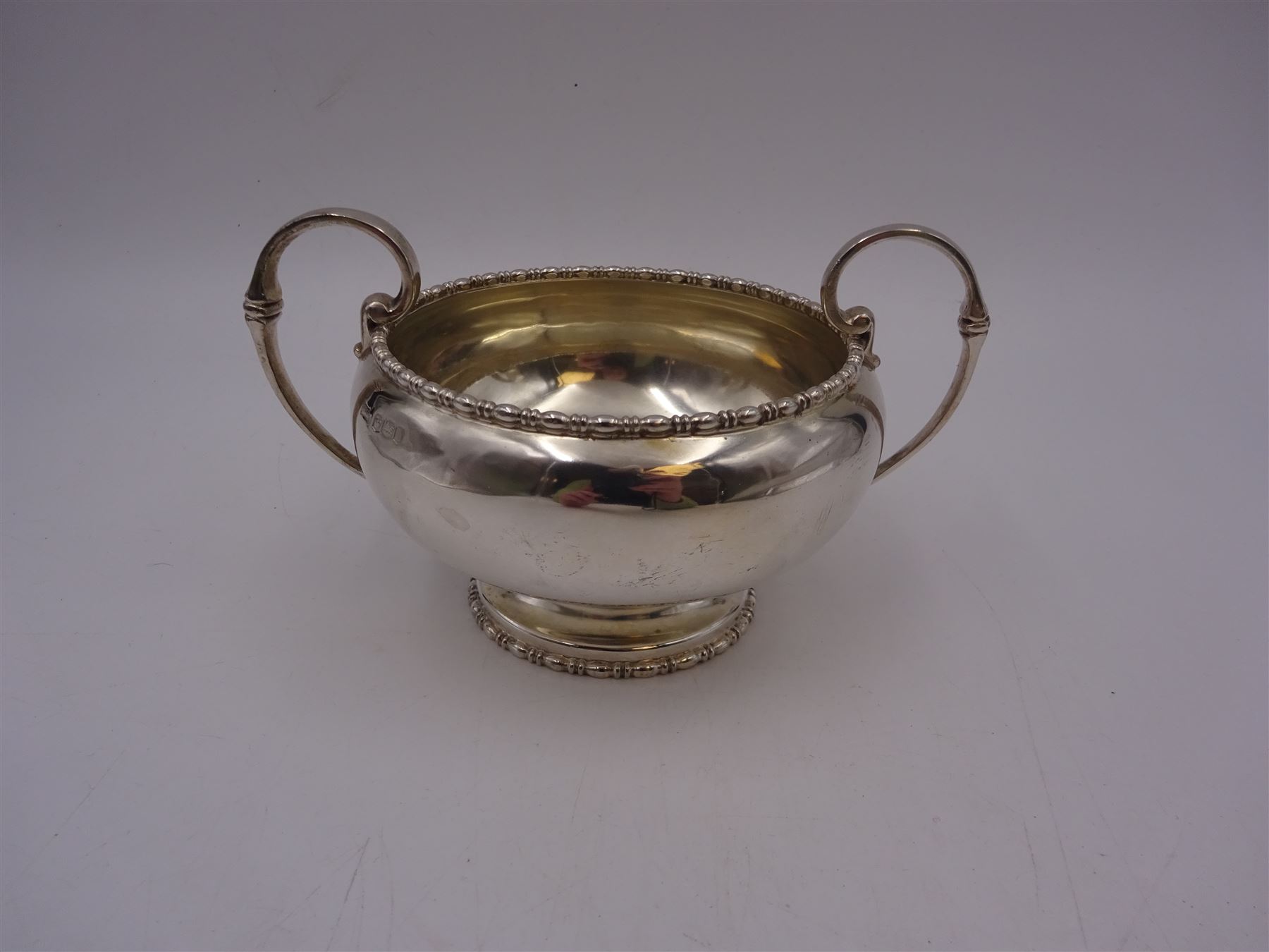 Early 20th century silver twin handled bowl, of plain bellied form with bead and dart rim and two C scroll handles, upon a circular foot, hallmarked Walker & Hall, Sheffield 1919, including handles H9.5cm